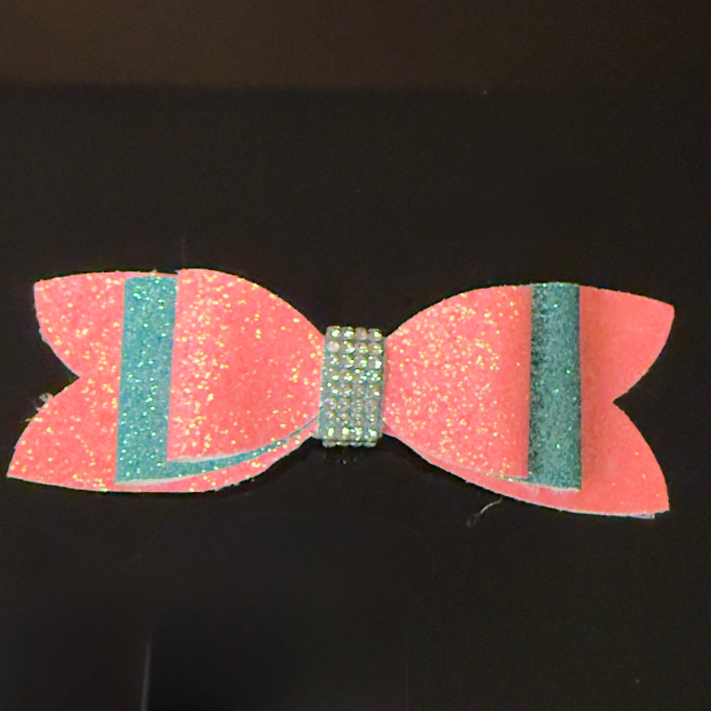 Pink and Turquoise glittery bow with green center on a black background