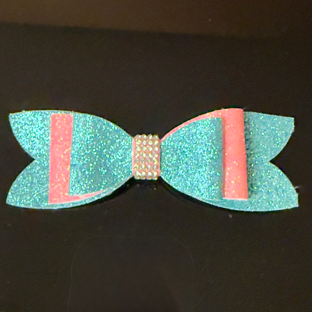 Turquoise and pink glittery bow on a black background